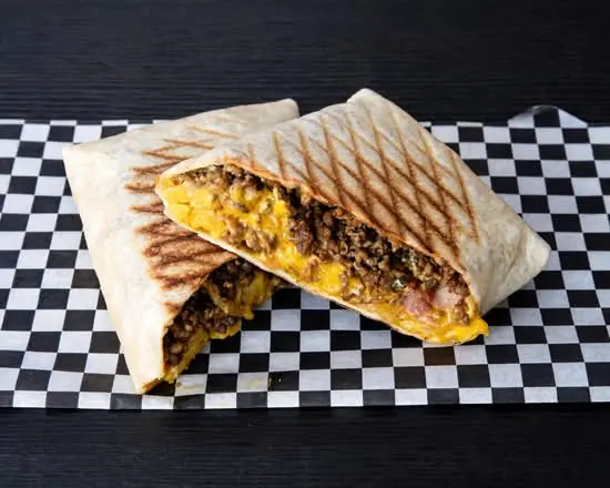 Taco Americano abierto sobre papel de cuadros, relleno de ternera, bacon halal y cheddar fundido